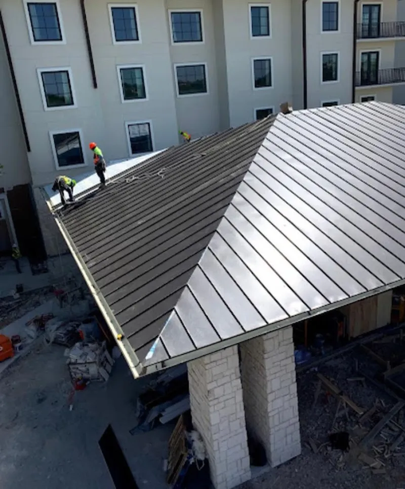 Crew installing standing seam metal roof panels on a commercial project in Paris
